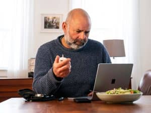 Diabetic checking insulin and glucose with salad at dinner table