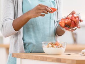 Woman adding strawberries to cereal