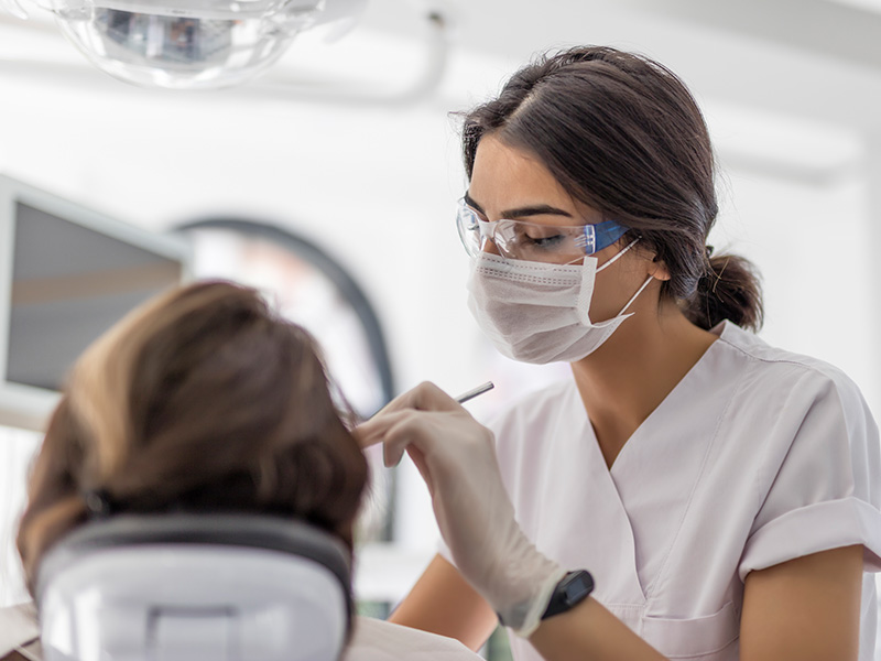 A female dental provider cleans a patient's teeth